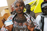 A South Sudanese voter shows her inked finger and registration card after casting a ballot in the Southu2019s historic referendum on independence, on the first day of polling 9 January, in Omdurman, near Khartoum, capital of Sudan. Approximately 51 percent of