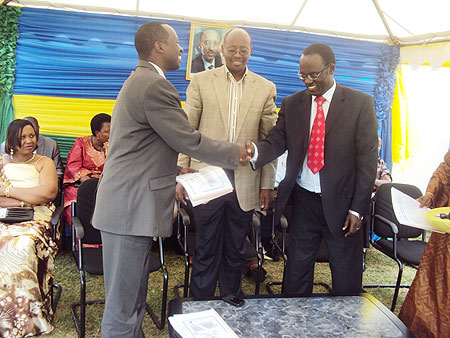 Ndayisaba (R) hands over to Munyentwari as Minister Musoni (C) looks on. (Photo: J.P Bucyensenge)