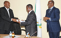 Out going Parmanent Secretary Eugene Barikana (L) hands over to the new PS Cyril Turatsinze as Local Government Minister James Musoni looks on. (Photo J Mbanda)