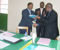 Bishop Nzakamwita hands over IPB's budget documents to Prof. Shyaka during the hand over ceremony on Saturday while IPB Rector Prof. Nyombayire aplands (Photo A.Gahene)