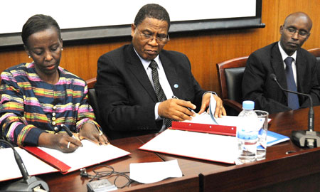 Foreign Affairs Minister, Louise Mushikiwabo (L), and COMESA Secretary General, Sindiso Ngwenya, sign the agreement as ICT Minister, Ignace Gatare, looks on. (Photo: J. Mbanda)