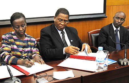 Foreign Affairs Minister, Louise Mushikiwabo (L), and COMESA Secretary General, Sindiso Ngwenya, sign the agreement as ICT Minister, Ignace Gatare, looks on. (Photo: J. Mbanda)