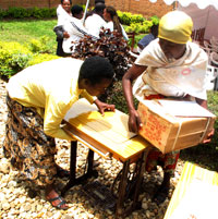 One of the students being helped by her parent to fix her new sewing machine (PhotoT.Kisambira)