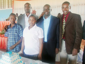 From R-L Mayor John Mugabo, Rev. Charles Mugisha Buregeya and HM John Africa pose for a photo with the school's best two pupils. (Photo: S. Rwembeho)