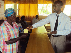 FINA bank Karongi Branch manager Chaste Nyilinkindi handing over a Mutuelle card to one of the beneficiaries (photo S Nkurunziza).