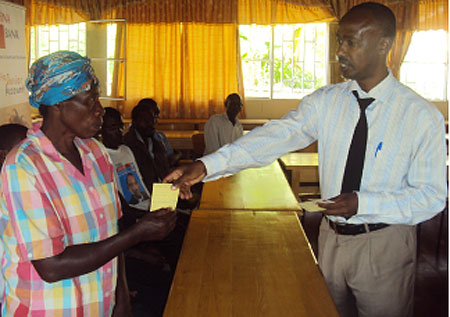 FINA bank Karongi Branch manager, Chaste Nyilinkindi handing over a Mutuelle card to one of the beneficiaries last week (File photo).jpg