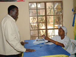 An electoral official attends to former Presidential aspirant Jean Damascene Ntawukuriryayo during the polls. Rwandau2019s use of volunteers has been lauded (File Photo)