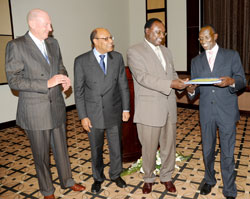 Minister Francois Kanimba (2 right) hands documents to Deputy Chief Justice Prof. Sam Rugege at the hand over ceremony of RICP outputs to respective institutions. Looking on are ICF co-chair Neville Isdell (L) and ICF CEO Omar Issa. (Photo by J Mbanda)