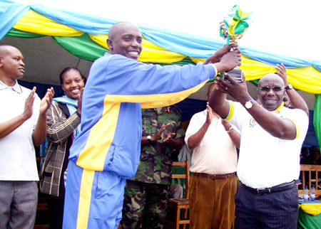 Kavumu Sector Executive Secretary, Jean d'Amour Kavange (L) receives trophy from Education Minister, Pierre Damien Habumuremyi. The Sunday Times / Courtesy 