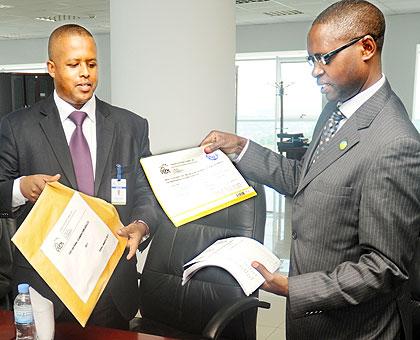 WDA Director General Jerome Gasana (L) hands over the 2011 TVET national Examination results to State Minister Mathias Harebamungu yesterday.  The New Times / J. Mbanda.