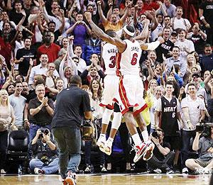 Dwyane Wade (3) and LeBron James leap in the air to celebrate the Heat's 93-91 overtime win over the Pacers in Miami. Net Photo.