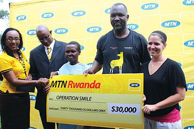 MTN staff, together with  Operation Smile Regional Director, Dr Aime Lokulutu (2nd R), at the handover of the cheque that facilitated the operation. Courtesy Photo.