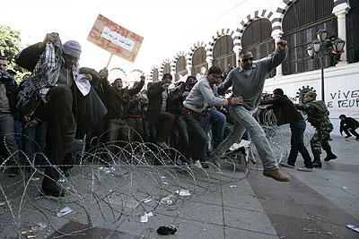 Tunisian protestors jump over a barbed wire into a protected area during a demonstration demanding a new government free of officials of the ousted regime of former president Zine el Abidine Ben Ali. Xinhua