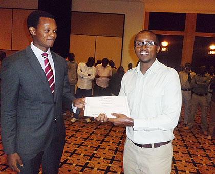 The Chairman of the Tourism Chamber at PSF, Edwin Sabuhoro (L)  handing a certificate to one of the trainees, Bilima Innocent. The NewTimes / Grace Mugoya.