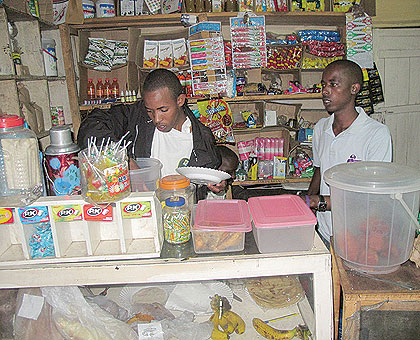 Nshimiyumukiza (R) with his cousin attending to customers in his kiosk. The New Times / S Nkurunziza.