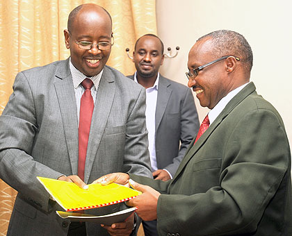 The Minister of Local Government, James Musoni, receives documents for the transfer of the Information docket from his Cabinet Affairs counterpart, Protais Musoni (R), yesterday. . The New Times/John Mbanda.