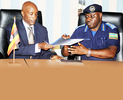 Uganda's Inspector General of Police, Kale Kayihura (L), and his Rwandan counterpart, Emmanuel Gasana exchange documents after signing an MoU at the Police headquarters yesterday. The New Times / John Mbanda.