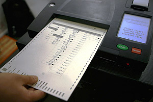 An election official demonstrates how a computerized election ballot is inserted into the computerized voting machine.  Net photo.