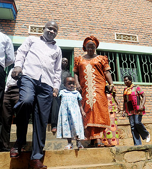 Josue Kumbi of Gikondo and his wife walk home with a child from the just closed Mpore Peff orphanage yesterday. The New Times, / John Mbanda.