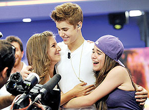 Lucky girls! Justin Bieber cuddles up to two female fans following an appearance on Spanish TV. Net photo.