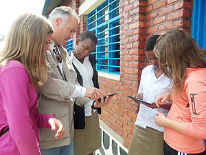 Mark Carleton, the Senior Vice President of Liberty Media Corporation (2nd L), demostrating to the students how the nook works. The New Times / S Nkurunziza.