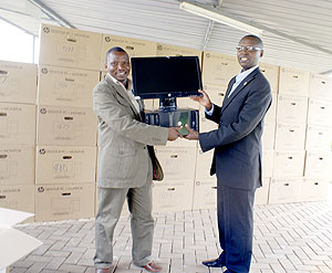 State Minister, Dr Mathias Harebamungu (R) while handing over a  computer to Athanase Sebageni, the Headmaster of Groupe Scolaire Mugambazi, in Rulindo District. The New Times / Courtesy.