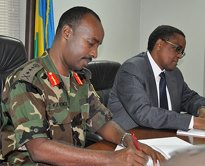 Chief of Defence staff Lt. Gen. Charles Kayonga (L) and NUR Rector Prof. Silas Lwakabamba sign the agreement yesterday. The New Times / Courtesy.