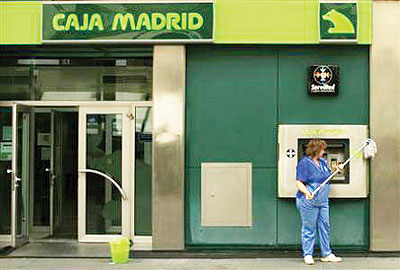 A cleaner cleans the facade of a Bankia-Caja Madrid bank branch in the Andalusian capital of Seville June 25, 2012. Net  photo.