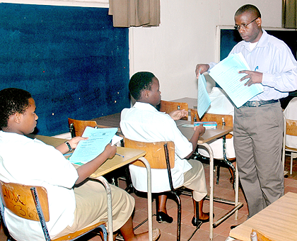 A teacher distributes exam papers.  The New Times / File.