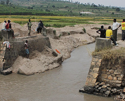 Residents look at the broken bridge. The New Times / E. Munyaneza.