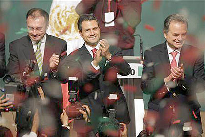 Enrique Pena Nieto (C), presidential candidate of the Institutional Revolutionary Party (PRI), stands next to campaign manager Luis Videgaray (L) and President of the PRI party Joaquin Coldwell as he greets supporters after exit polls showed him in first 