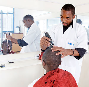 A barber attending to a customer. Rural electrification is boosting business. The New Times / Timothy Kisambira.