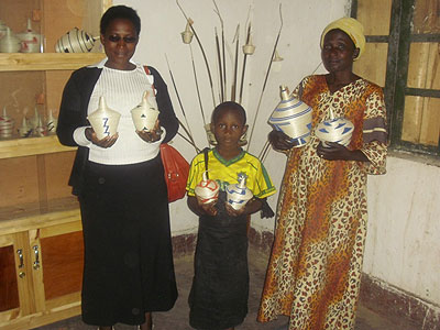 Eugenia Mukankurayija ( R ) displaying some of her products in a store with one of the buyers and granddaughter. The New Times / Patience Uwitonze.