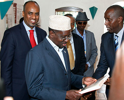 Somali President Sheikh Shariff Ahmed admiring a book that contains pictures of the Rwandan culture at the  Museum of Natural History in Kigali. The New Times / Timothy Kisambira.