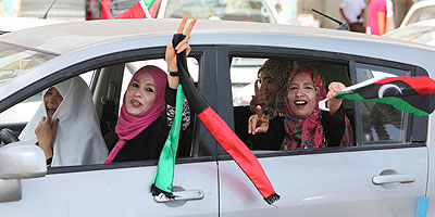 Libyan women celebrate the holding of elections by waving a Libyan flag and flashing the victory sign as they drive in Tripoli, Libya, July 7, 2012. Net photo.