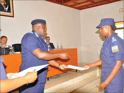 IGP Emmanuel Gasana hands a certificate to one of the graduates at the police headqarters,  yesterday. The New Times / Courtesy.