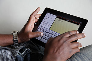 A person using an Ipad. Broadband will make use of such gadgets faster and more effective.  The New Times / Timothy Kisambira.