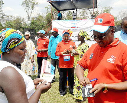 Minister Protais Musoni pulls out a business card from his wallet to give it to Jeanne Mukandahiro of Niboye Sector, Kicukiro District, whom he gave a cheque of Rwf100, 000 to help boost her business. The New Times / John Mbanda. 