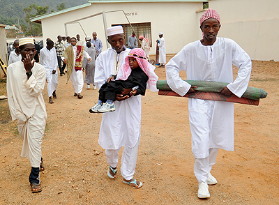 A father carries his son home after Eid prayers on Sunday.  The New Times / John Mbanda.