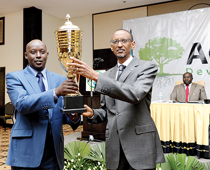 President Kagame handing a trophy to Paul Jules Ndamage, Mayor of Kicukiro, whose district emerged the best performer in the country. The New Times/Village Urugwiro.