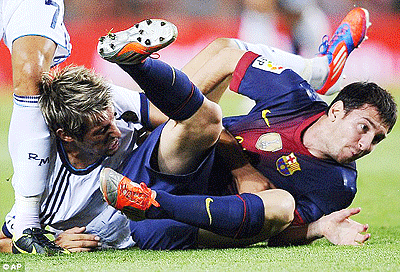 Messi tussles with Fabio Coentrao on the turf. Net photo.