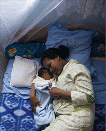 A woman with her baby sleeping under a treated mosquito net.  The New Times / File.