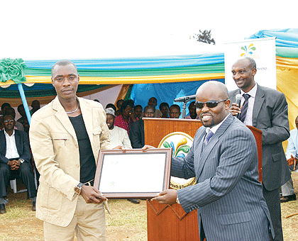 The Minister of Youth and ICT, Jean Philbert Nsengimana (R), awards one of the best tax payers with a certificate. The New Times/S. Rwembeho.