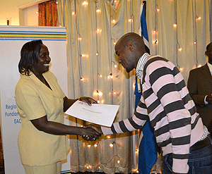 EAC Deputy Secretary Jessica Eriyo hands over an appointment certificate to New Times' Gashegu Muramira as the CEO Pan African Lawyers Union Don Deya looks on. The New Times/Courtesy