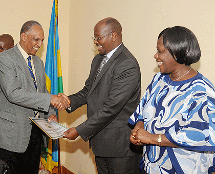 Demobilisation and Re-Integration commission Chairman Jean Sayinzoga (L) presents his performance contract document to Local Government Minister James Musoni as State Minister Alvera Mukabaramba looks on. The New Times / John Mbanda.