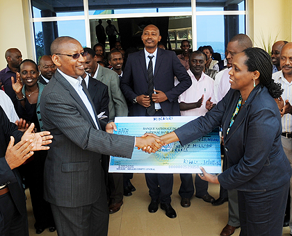 Finance Minister John Rwangombwa (L) receives a dummy cheque from Agriculture Minister Agnes Kalibata as other ministry staff look on yesterday. The staff contributed Rwf420 million towards the Agaciro Development Fund. The New Times / John Mbanda.