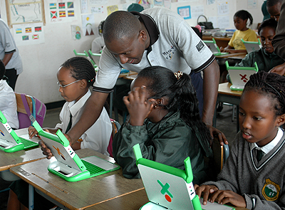 A teacher guides pupils on how to use OLPC computers. The New Times / File.