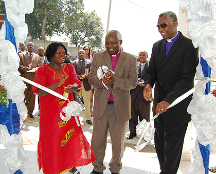 Archbishop of the Anglican Church of Rwanda Onesphore Rwaje cuts a ribbon at the commissioning of the commercial complex yesterday. He is flanked by Bishop Laurent Mbanda of Shyira Diocese and Musanze District Mayor Winfrida Mpembyemungu. The New Times / 