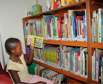 Pupil picks a book from the shelf at  Kigali public Library at the beginning of the Reading Week yesterday. The New Times / John Mbanda.