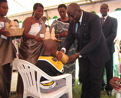 Prime Minister Pierre Damien Habumuremyi serves milk to a little boy during the launch of the Family Campaign Week in Byimana Sector, Ruhango District, on Tuesday. The New Times / JP Bucyensenge.